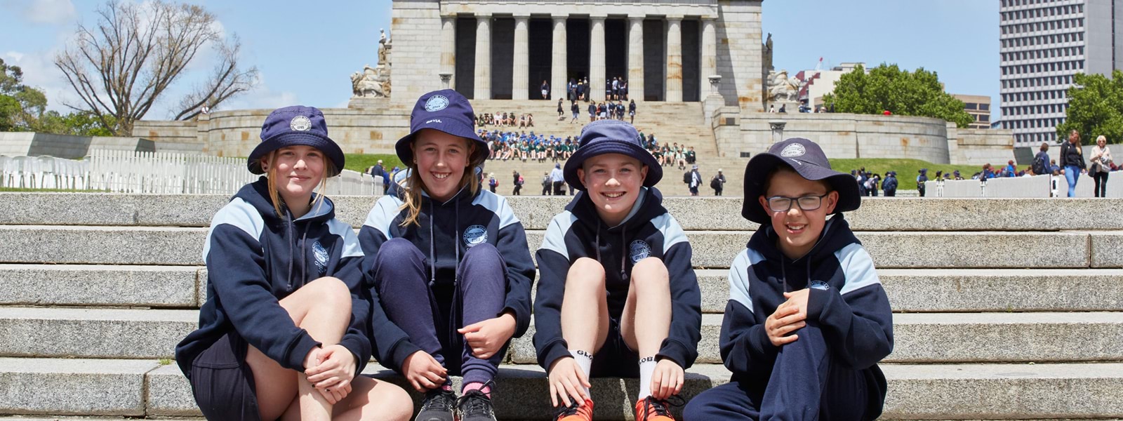 Primary students sit on steps of the Shrine of Remembrance