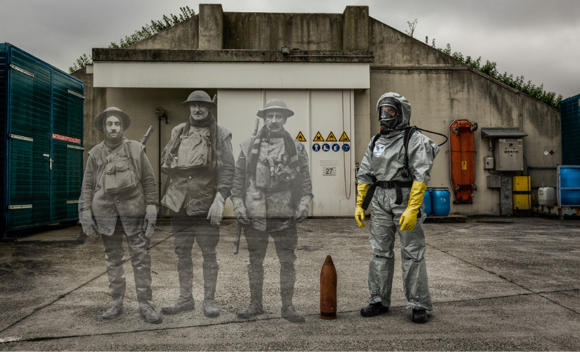 An artwork by Ian Alderman. On the right is someone from Belgium's bomb disposal team. They are wearing a full length silver protective jumpsuit, long yellow gloves and a helmet with a mas. On the floor next to them is a bomb. Superimposed on the left of the image are three soldiers from the First World War. They are all in full uniform with hats and boots. This image is black and white, and their silhouettes have been faded to blend into the image. In the background is a concrete bunker and cloudy skies. 