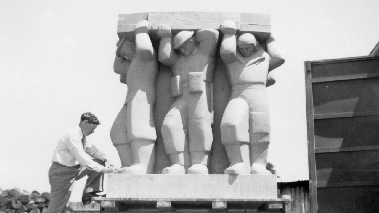 A man steps up to stand next to the cenotaph sculpture during construction.