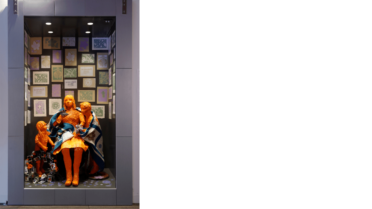 Installation view of a mixed media artwork of a mother and children wrapped in the quilted blanket.